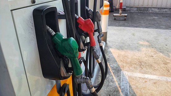 Green red and yellow petrol fuel pistols at a gas station